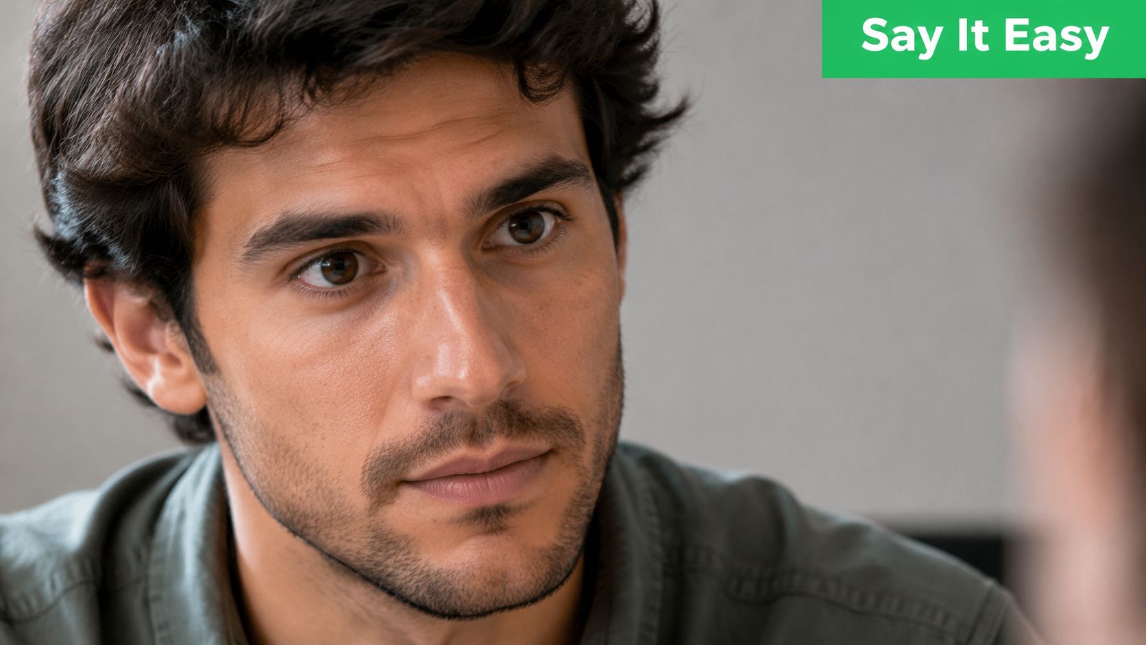 A close-up shot of a thoughtful young man with dark hair looking intently during a conversation.